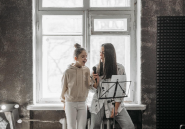 Girl practicing singing with her mentor