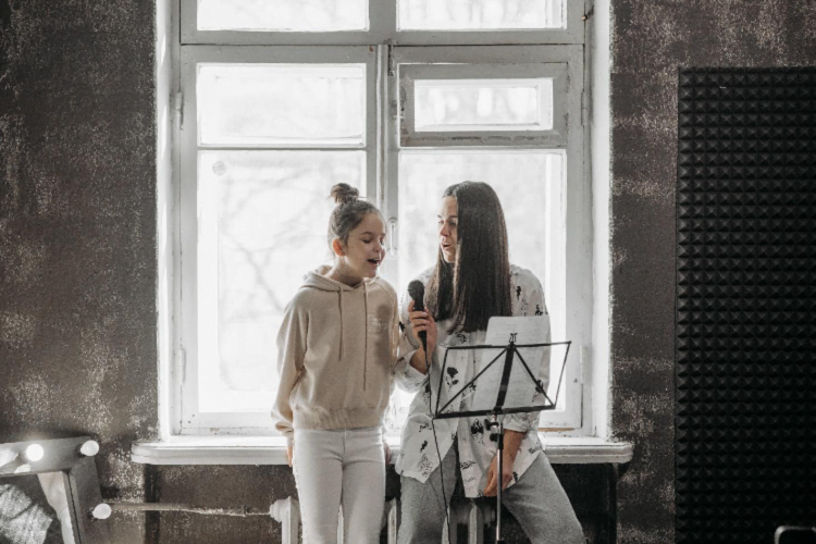 Girl practicing singing with her mentor