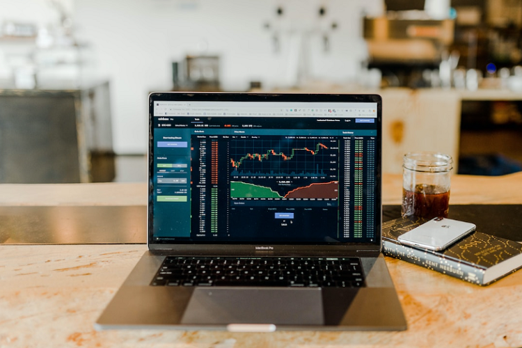 A Kagi chart and other stock data shown on a laptop with a book, phone, and drink next to it.